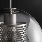 Glass pendant light with slim metal stem lit warmly in a room