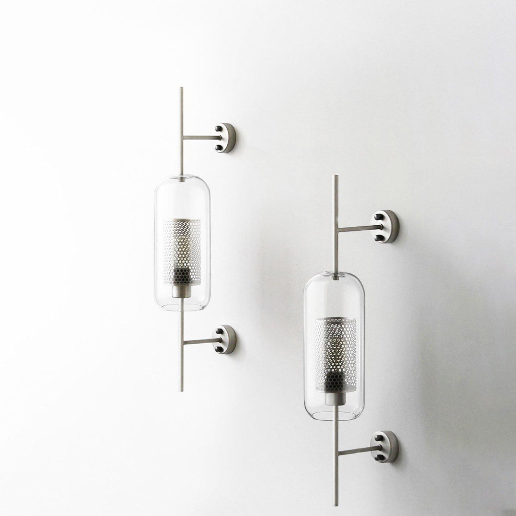 Hand-cut glass wall light with slim metal stem lit gently