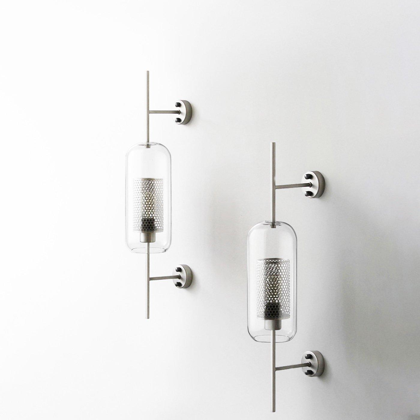 Hand-cut glass wall light with slim metal stem lit gently