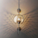 Hand-cut glass wall light glowing warmly against a pale wall