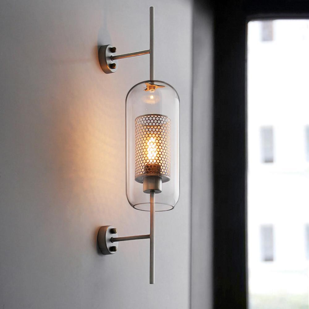 Glass wall light with metal stem casting warm light indoors