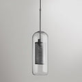 Capsule glass pendant light in silver glowing warmly over a table