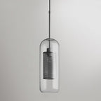 Capsule glass pendant light in silver glowing warmly over a table