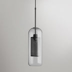 Glass pendant light with slim metal stem lit warmly in a room