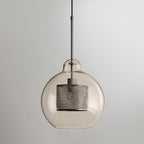 Glass pendant light with metal stem casting warm light on a table