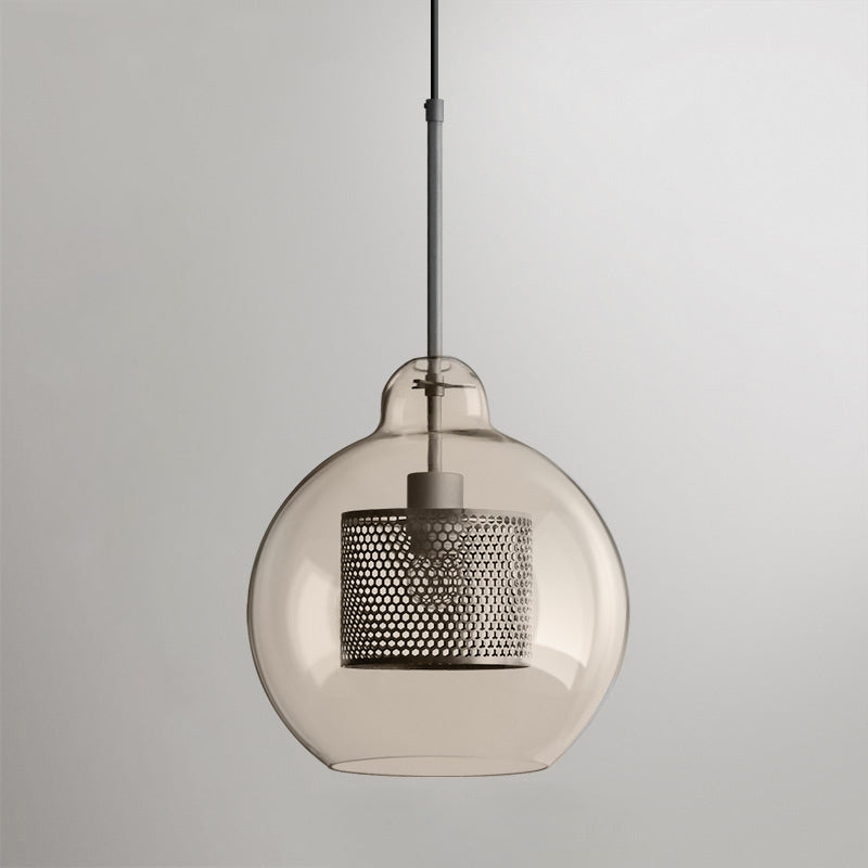 Glass pendant light with metal stem casting warm light on a table