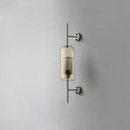 Glass wall light with metal stem casting warm light on a wall