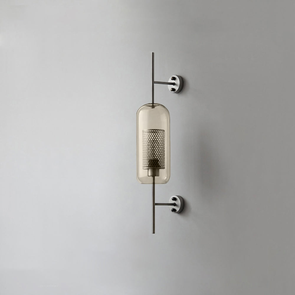 Glass wall light with metal stem casting warm light on a wall