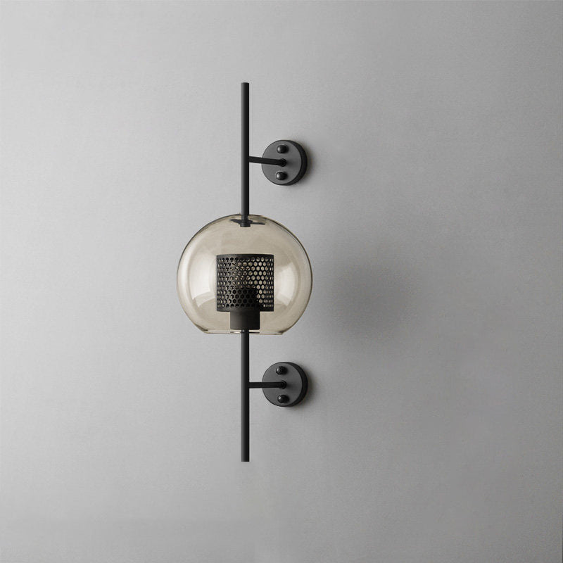Glass wall light with slim metal stem lit softly beside a wall