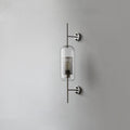 Capsule glass wall light in silver with clear shade glowing softly