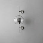 Sphere glass wall light in silver with clear glass shade lit warmly