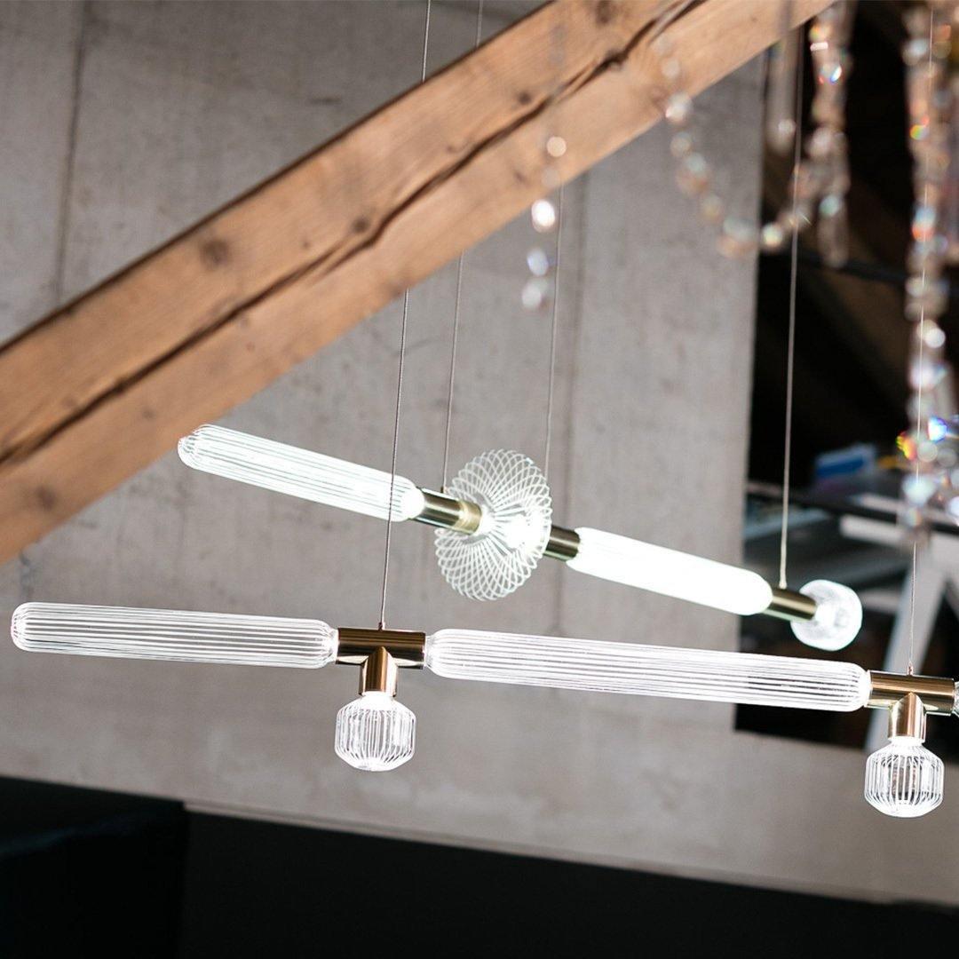 Two Clérachic pendants hang lit beside a wooden beam, their crystal rods catching the light.