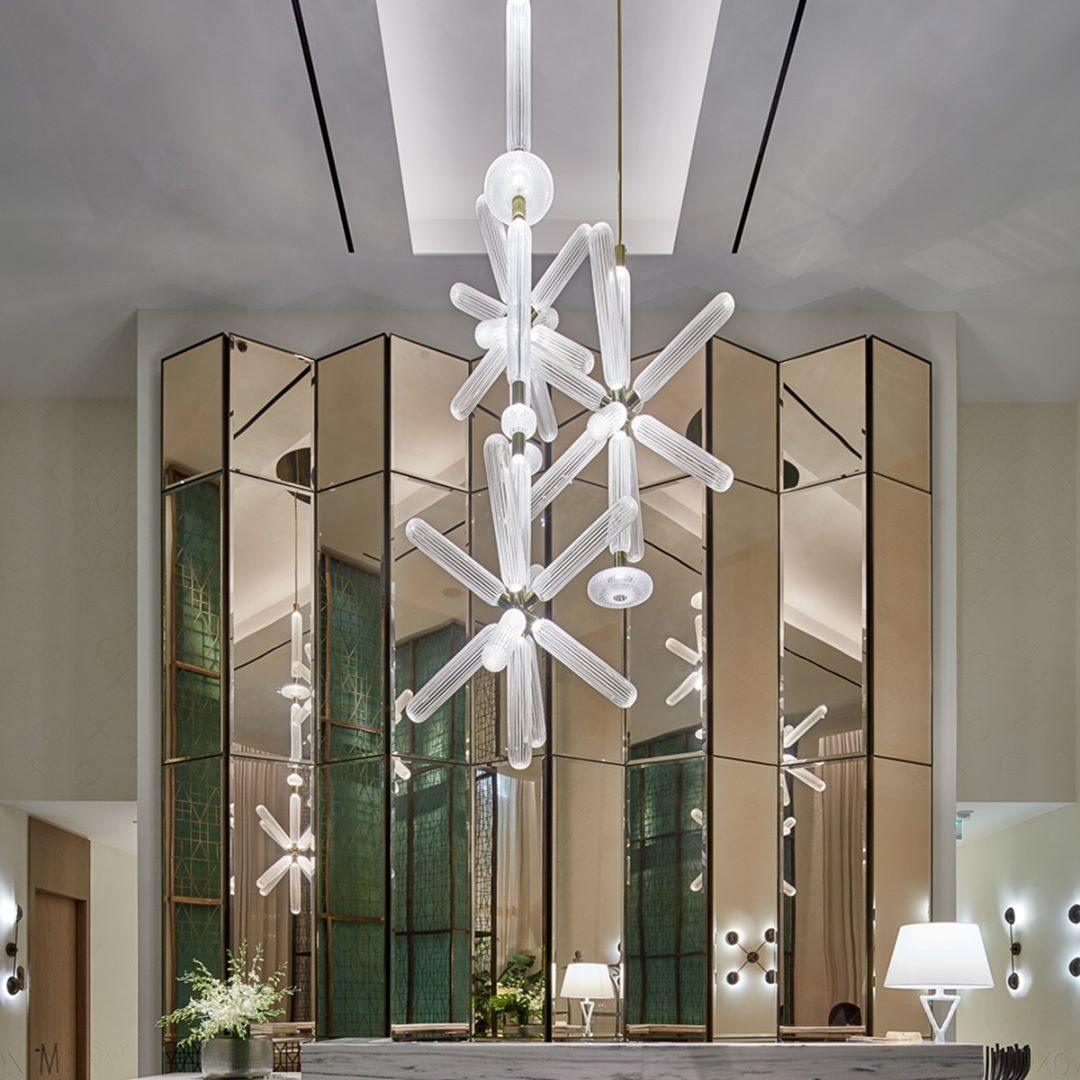This Clérachic pendant hangs lit before a folding mirrored screen in a hotel lobby.