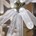 Close view of the champagne-gold joint where this Clérachic pendant's ribbed rods radiate outward.