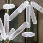 Close view of this Clérachic pendant's ribbed rods and a round disc cap against a green screen.