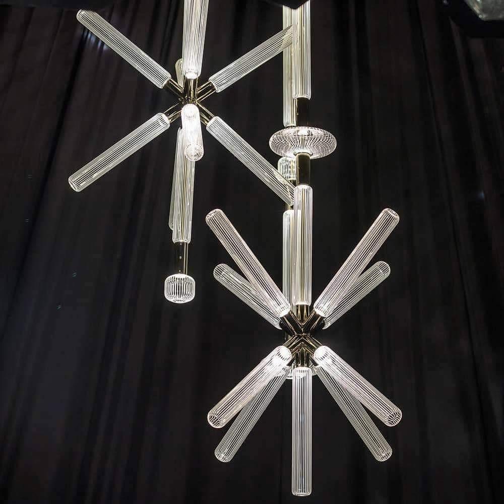Three Clérachic pendants cluster at different drops, their crystal rods lit against dark drapery.