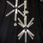 Three Clérachic pendants cluster at different drops, their crystal rods lit against dark drapery.