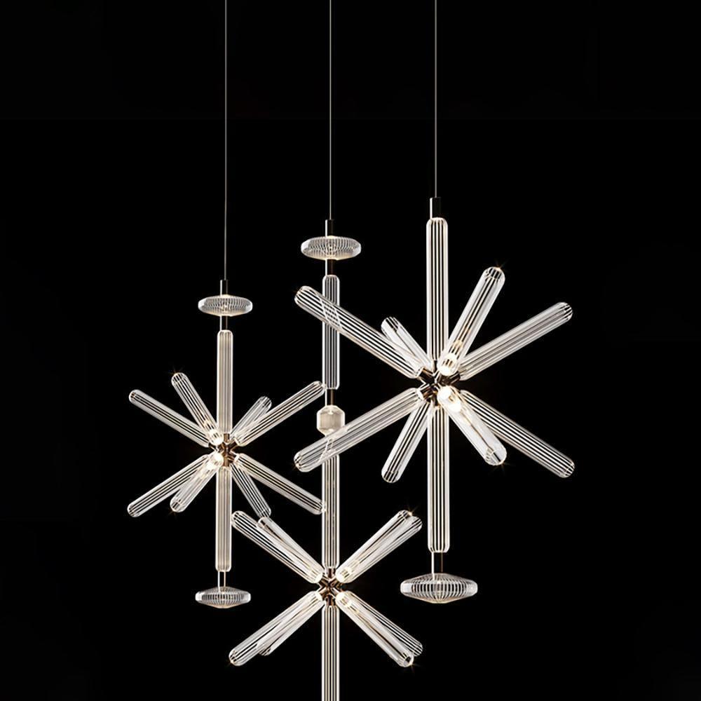 Three Clérachic pendants group together, their ribbed rods glowing against a black backdrop.