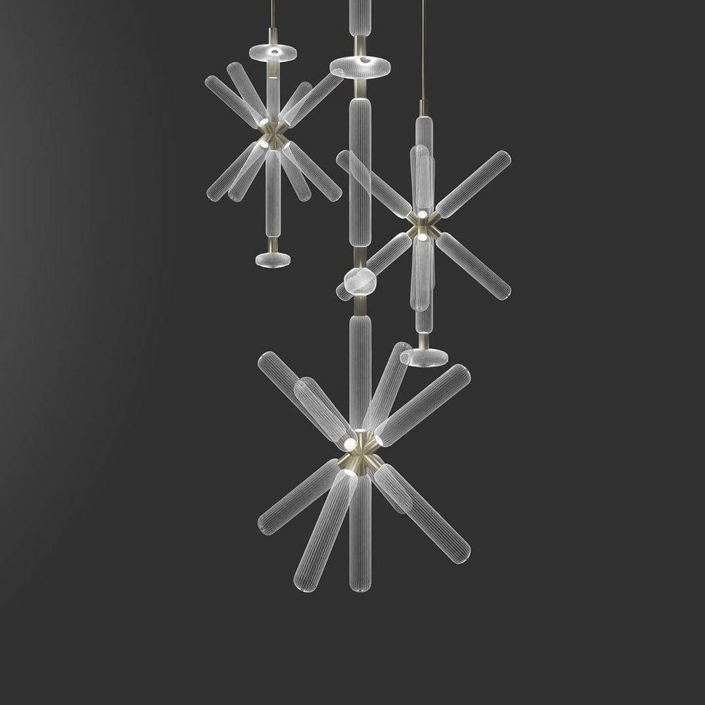 Three smaller Clérachic pendants cluster together, their crystal rods lit against a grey backdrop.