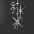 Three smaller Clérachic pendants cluster together, their crystal rods lit against a grey backdrop.