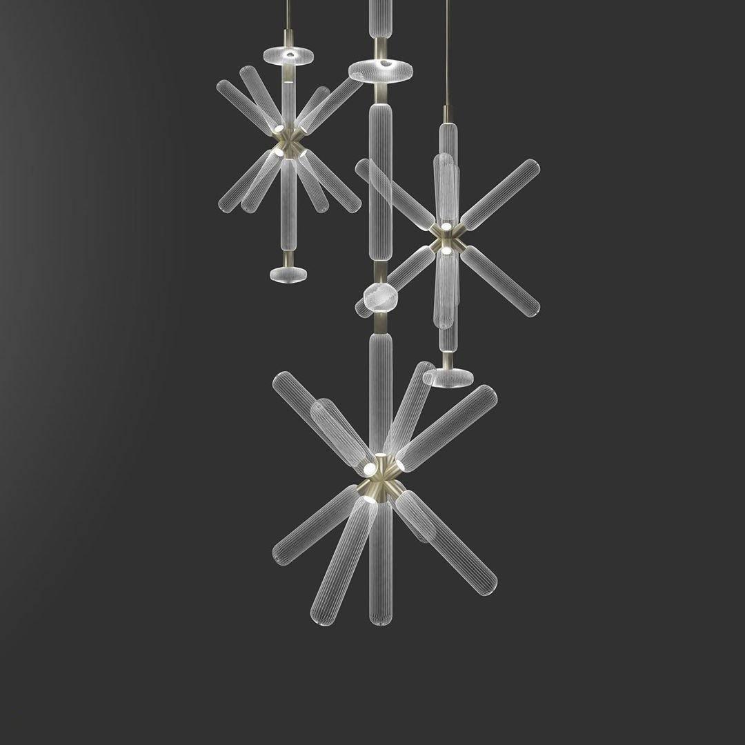 Three smaller Clérachic pendants cluster together, their crystal rods lit against a grey backdrop.