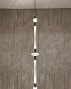 This Clérachic pendant hangs against a stone-tiled wall, its slim rod broken by a round disc joint.