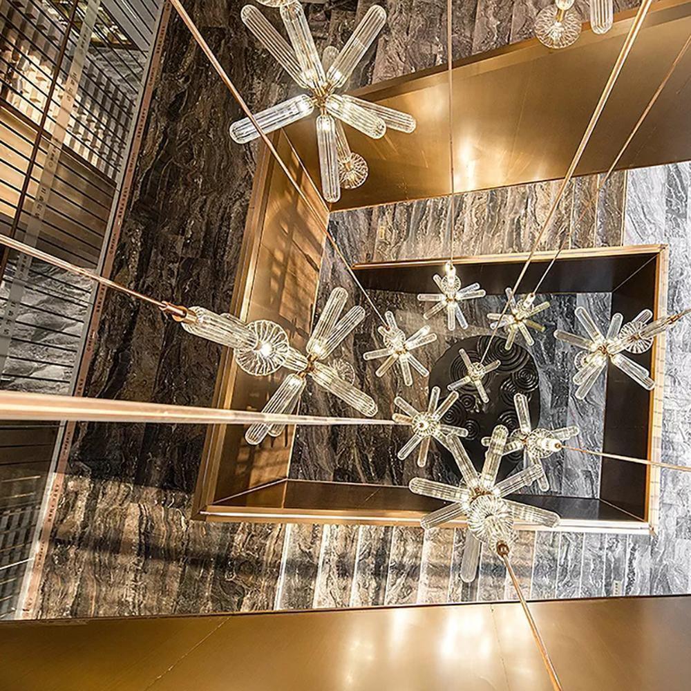 Looking down a stairwell at several Clérachic pendants lit against dark marble and brass trim.