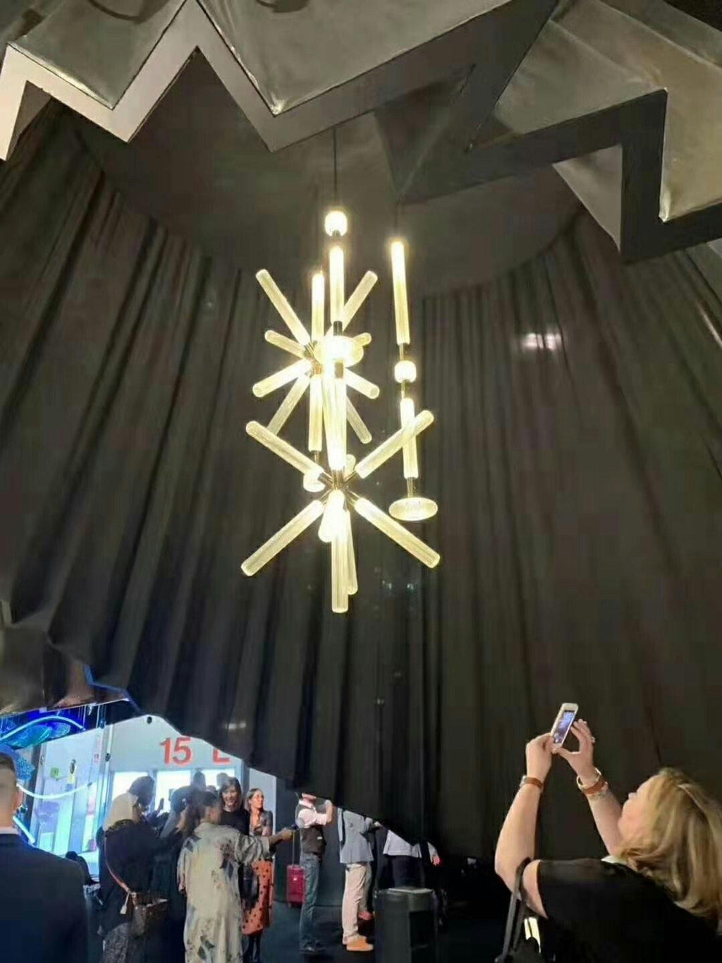 This Clérachic pendant hangs lit at a trade-show display, its crystal rods glowing above onlookers.