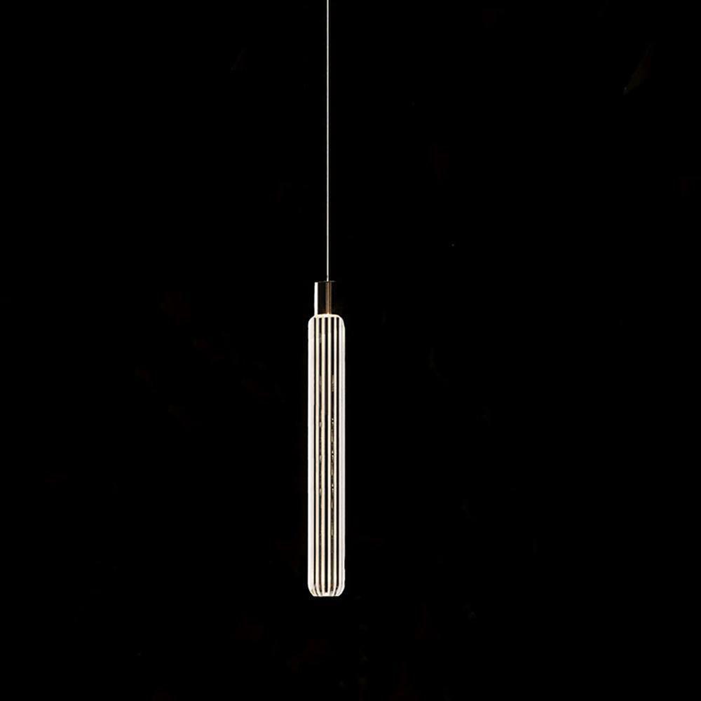 This Clérachic pendant's fluted glass cylinder hangs lit against a plain black backdrop.