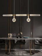 Above a marble dining table set with glassware, this Clérachic pendant hangs lit.