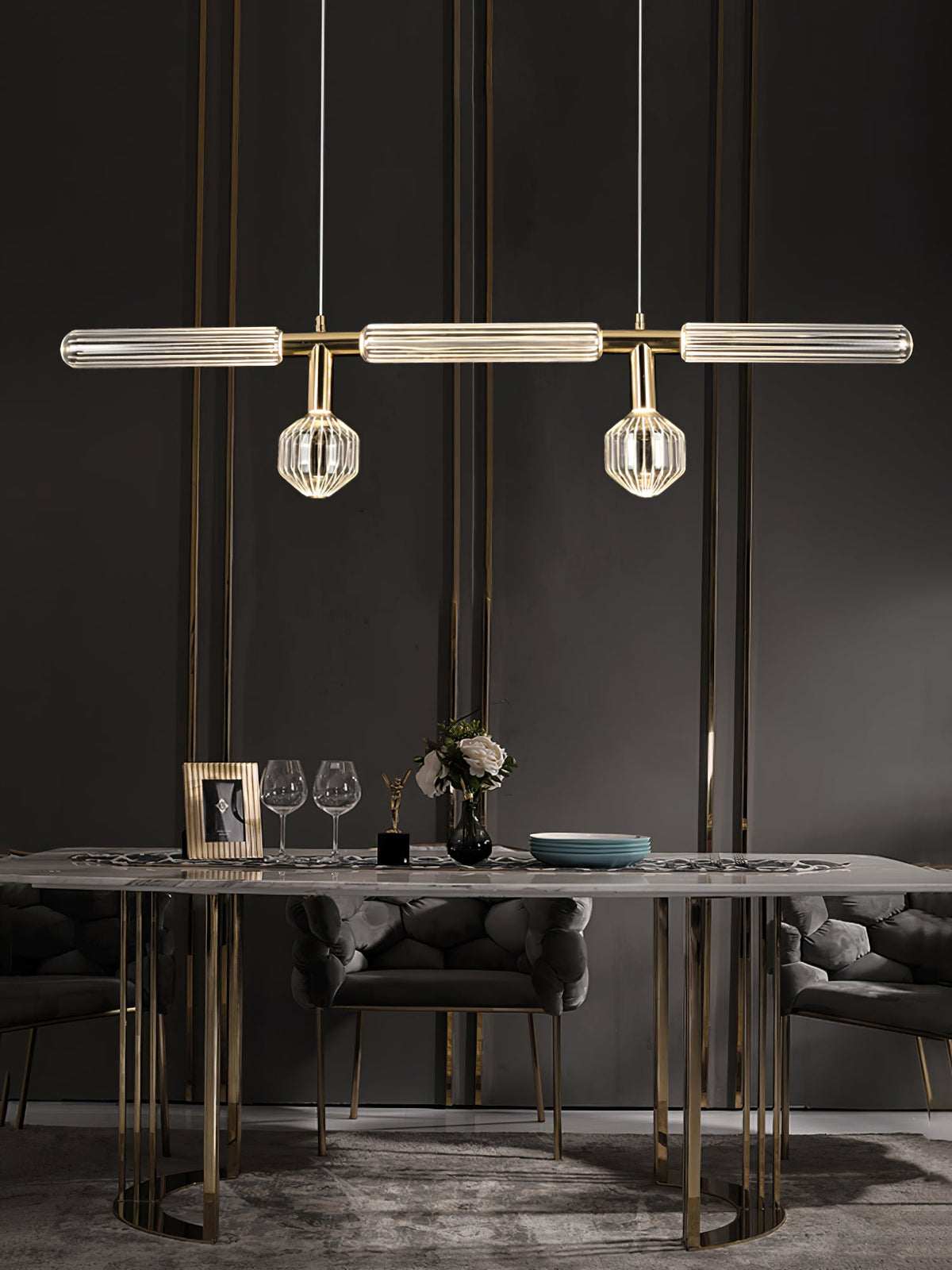 Above a marble dining table set with glassware, this Clérachic pendant hangs lit.