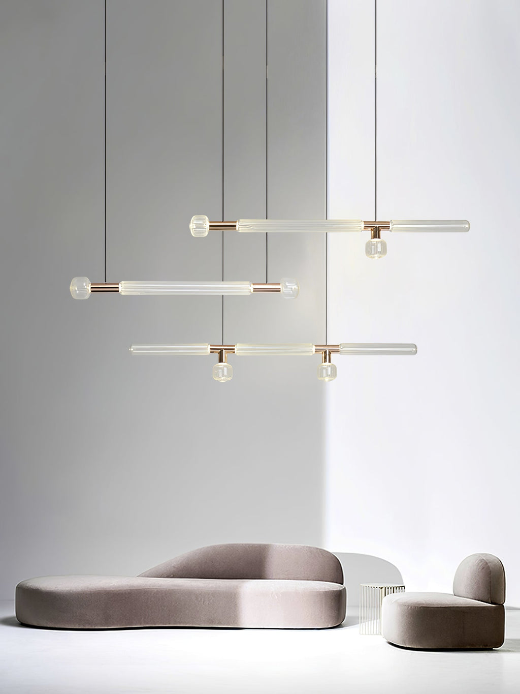 Small Clérachic pendants, linear and single-rod, cluster above a low curved sofa.