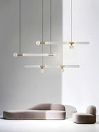Small Clérachic pendants, linear and single-rod, cluster above a low curved sofa.