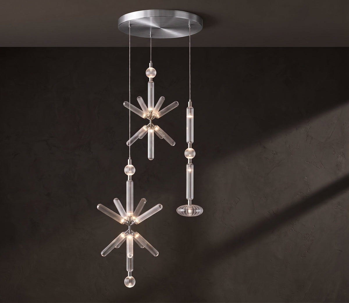 A crystal burst and a fluted rod, both Clérachic pendants, hang from a nickel ceiling plate.
