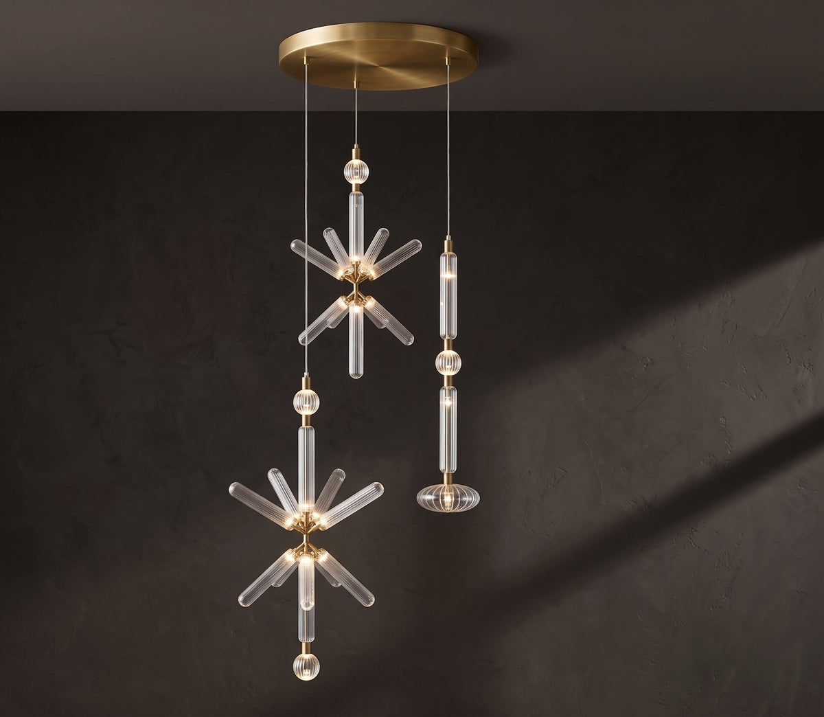 A crystal burst and a fluted rod, both Clérachic pendants, hang from a brass ceiling plate.