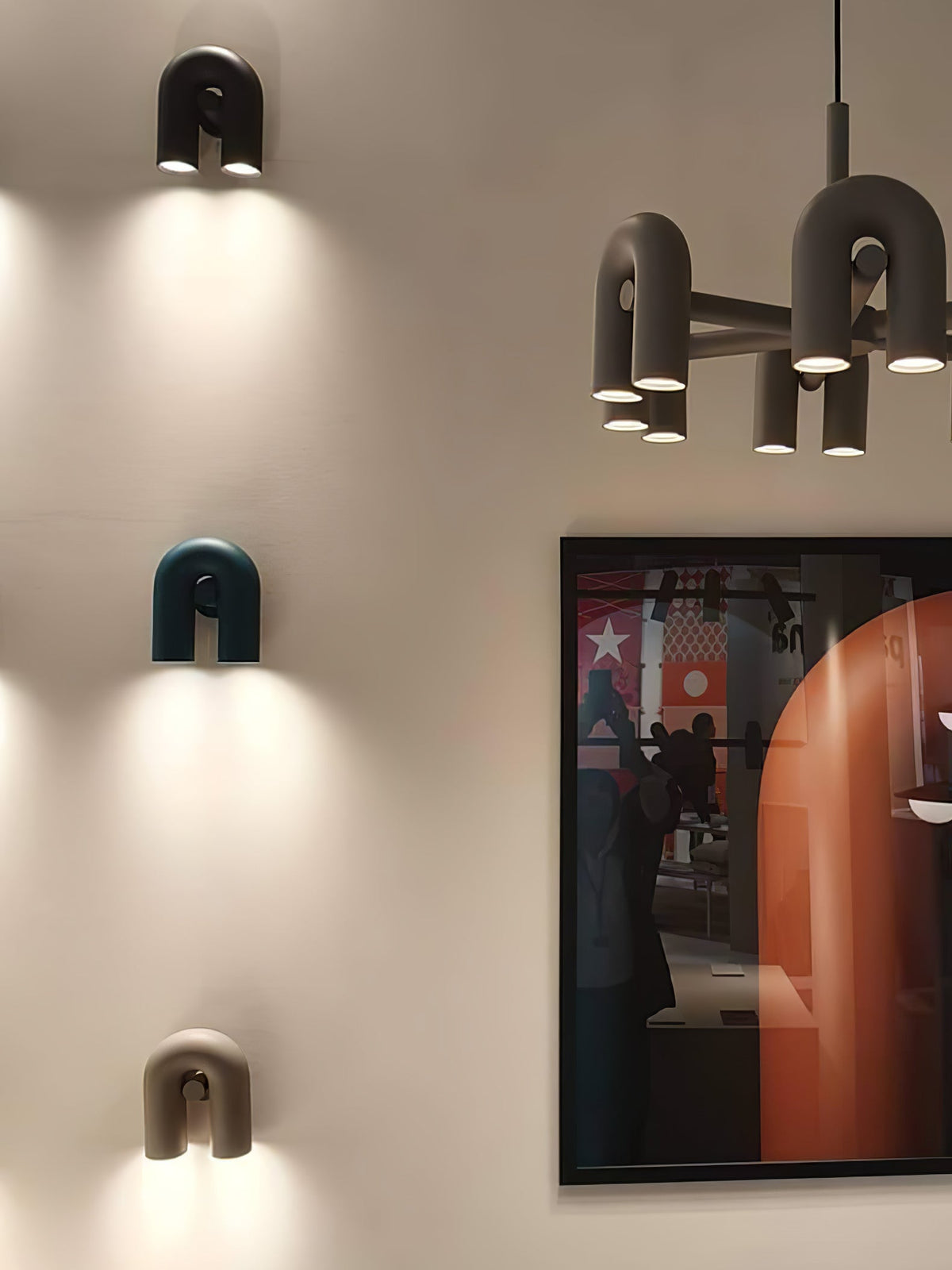 Grey, teal and terracotta Clérachic wall lights stack on a wall beside a multi-head floor lamp and framed poster.