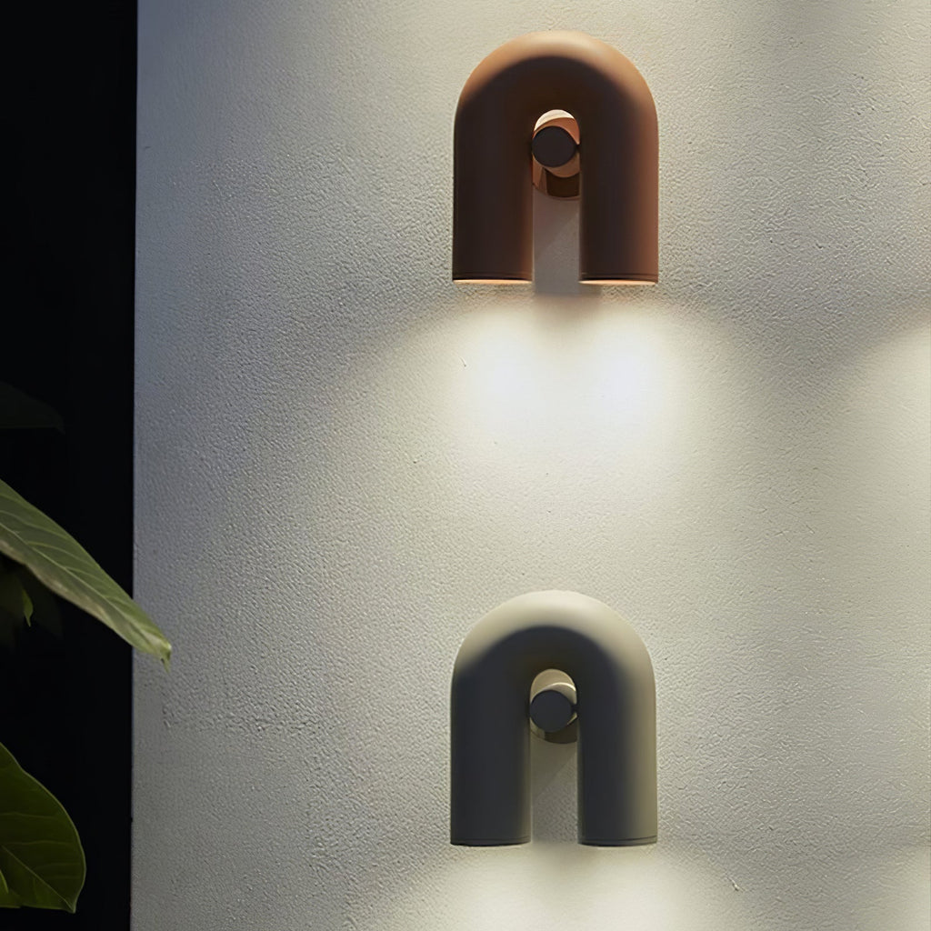 Two Clérachic wall lights, terracotta above black, light a textured plaster wall with warm downward glow.