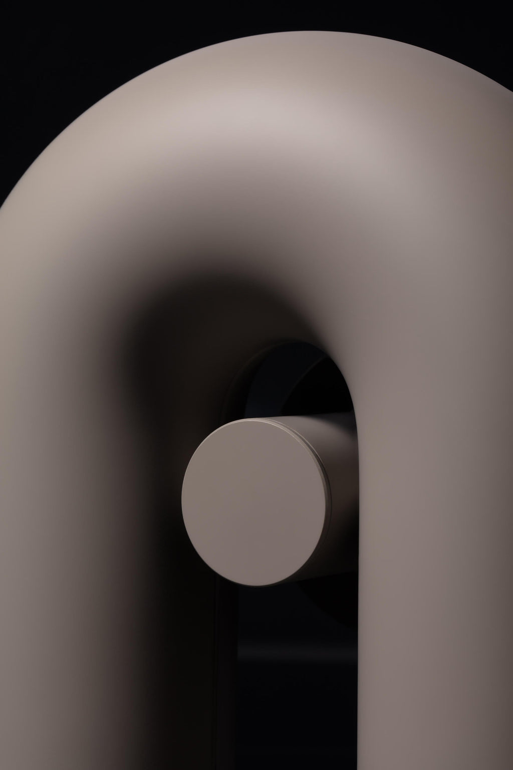 Extreme close-up of the curved tube and round mounting plate on this grey Clérachic wall light.