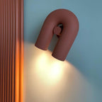 Seen from a lower angle, this terracotta Clérachic wall light warms a blue wall beside a fluted panel.