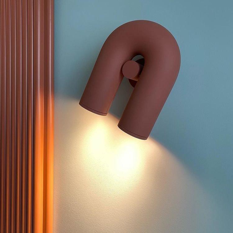 Seen from a lower angle, this terracotta Clérachic wall light warms a blue wall beside a fluted panel.