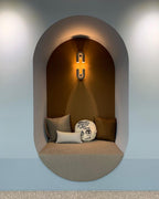 In a mustard-toned alcove with a cushioned bench seat, this terracotta Clérachic wall light glows warm overhead.