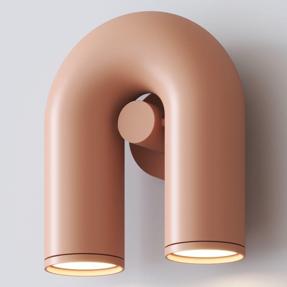 Full-length detail of this terracotta Clérachic wall light, showing the U-shaped tube and central swivel joint against a plain backdrop.