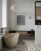 This Clérachic wall light sits small and pale on a bathroom wall, beside a freestanding tub and framed artwork.