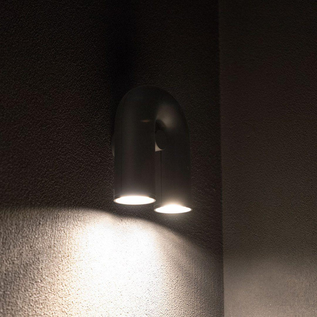 Close view of this Clérachic wall light in black, its twin spotlight heads casting cool white light in a dim room.