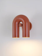 This Clérachic wall light in terracotta is angled to show its swivel joint and twin spotlight heads.