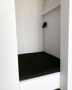 This Clérachic wall light in black mounts small and unlit above a built-in bench with a dark cushioned seat.