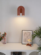 This terracotta Clérachic wall light lights a console styled with flowers, a framed print and a small figurine.