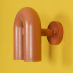 Full side profile of this terracotta Clérachic wall light shows its mounting arm against a yellow backdrop, unlit.