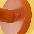 Extreme close-up of the swivel screw joint on this terracotta Clérachic wall light, against a yellow backdrop.