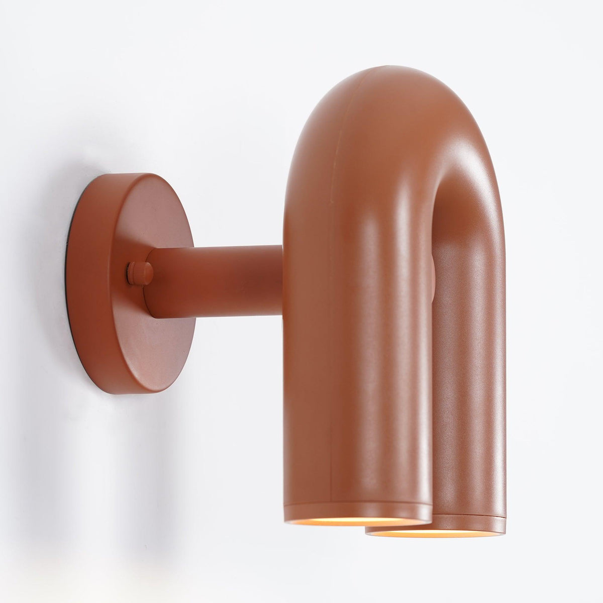 Viewed from the side, this terracotta Clérachic wall light shows its round mounting plate against white.